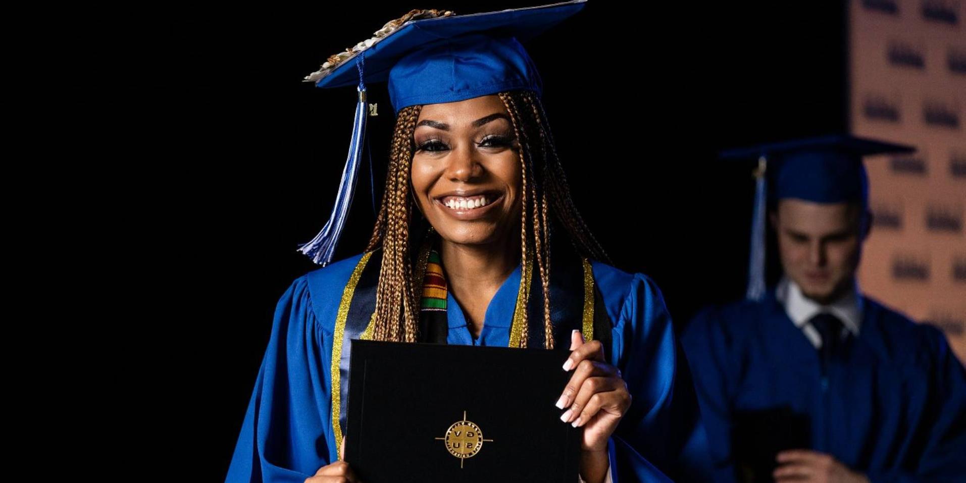 Woman smiling during graduation with diploma in hand